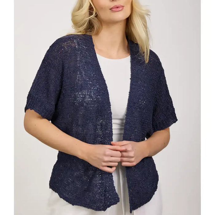 Woman wearing a navy blue knitted cardigan over a white top on a light gray background