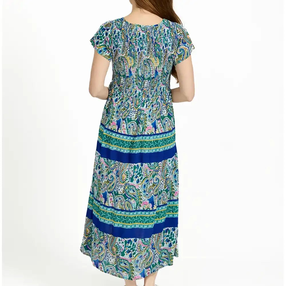 A woman wearing a long, short-sleeved maxi dress with a colorful paisley and floral print, shown from the back against a plain white background.