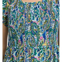 A close-up of a short-sleeve dress featuring a colorful paisley and floral print with blue, green, pink, yellow, and white tones, with a smocked bodice.