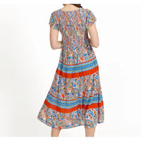 A woman modeling a short-sleeved midi dress from the back, featuring a colorful paisley pattern with prominent orange-red horizontal stripes, set against a plain white background.