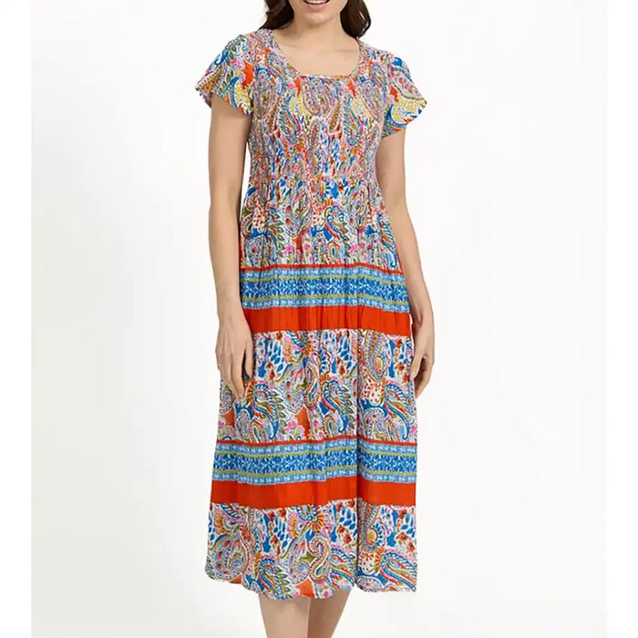 A woman wearing a short-sleeve midi dress with a colorful paisley and geometric print, featuring orange-red horizontal stripes, against a plain white background.