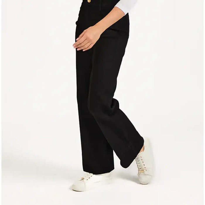 Person wearing black wide-leg pants with white sneakers on a white background