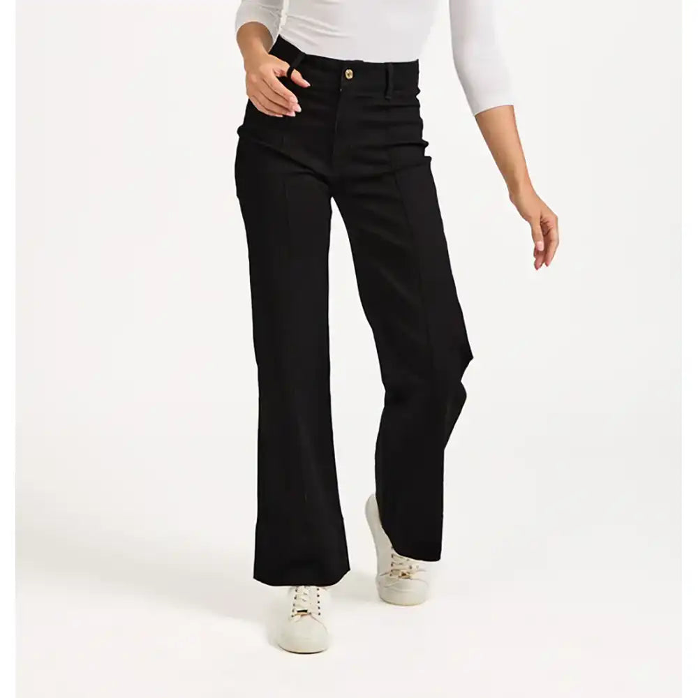 Person wearing black flared jeans on a white background