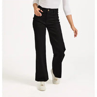 Person wearing black flared jeans on a white background