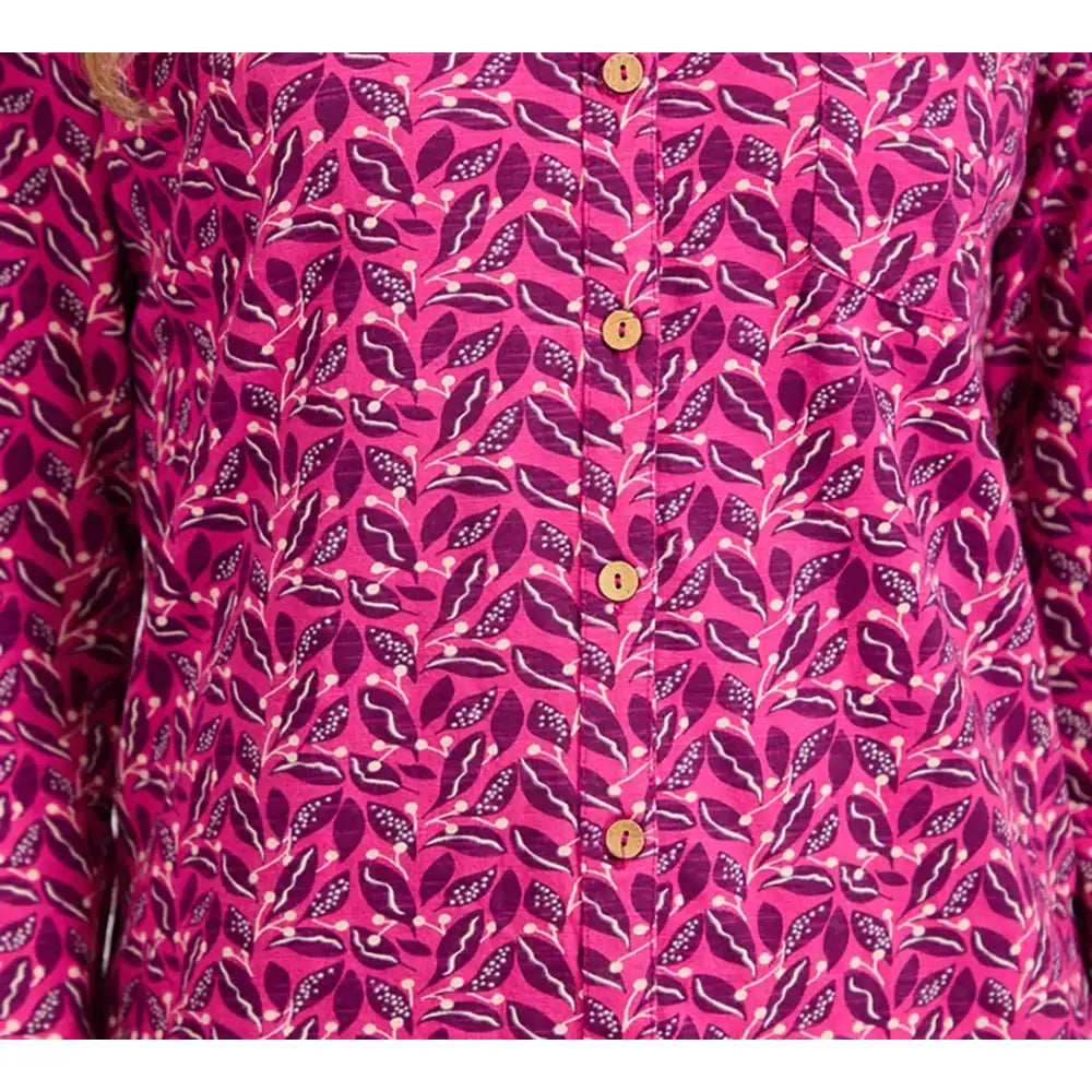 A close-up of a pink button-up shirt with a magenta and purple leaf pattern, featuring gold buttons down the front.