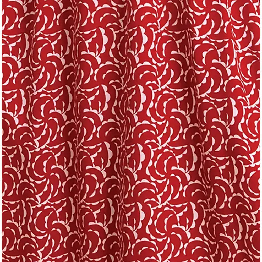 Red curtain fabric with a repeating white floral or scallop pattern, shown hanging with soft folds.