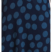 A close-up of a dark navy blue textured fabric with a repeating pattern of medium blue polka dots.