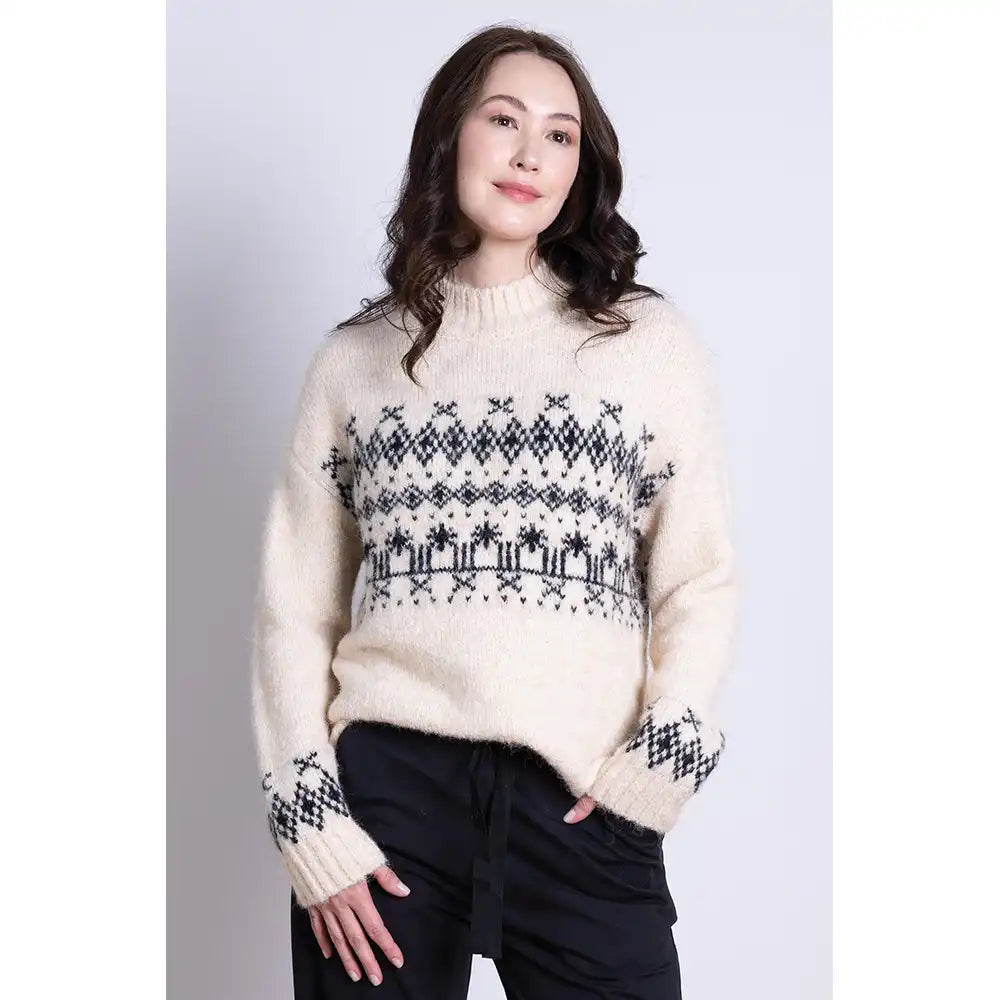 Woman wearing a cream sweater with black pattern made of recycled fibres and wool against a white background