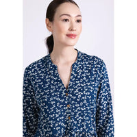 View of neckline of woman wearing a blue floral patterned tunic dress on a white background