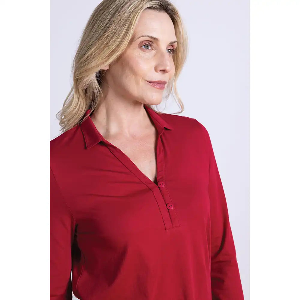 Woman wearing a red collared top with 2 buttons against a white background
