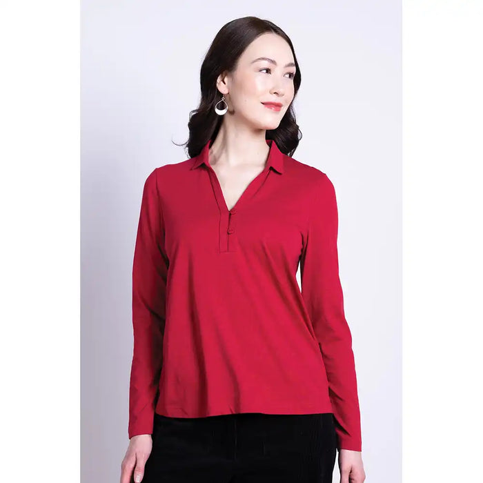 Woman wearing a red long-sleeve collared shirt against a white background