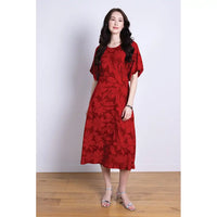 Woman wearing a red and burgundy floral dress against a white background