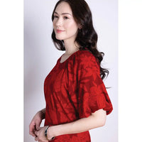 Woman wearing a red floral dress with short puff sleeves against a white background