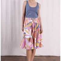 Person wearing a colorful patterned skirt with a plain background