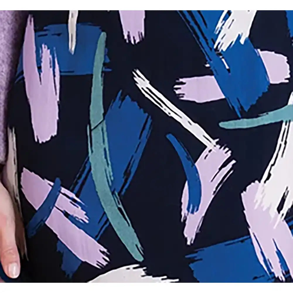 A close-up of a garment featuring an abstract brushstroke pattern in navy, blue, teal, and light purple, with a hand partially visible on the left edge.