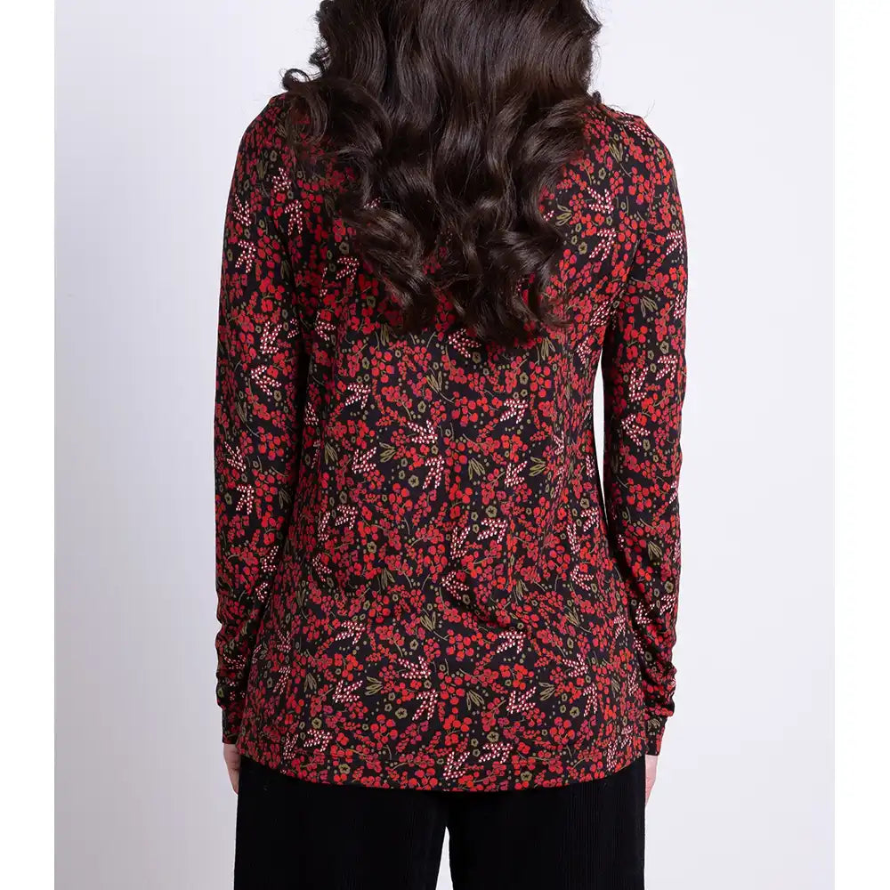 Person wearing a red and black floral long-sleeve top on a white background