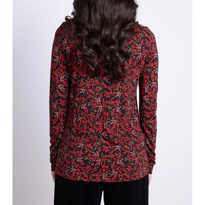 Person wearing a red and black floral long-sleeve top on a white background