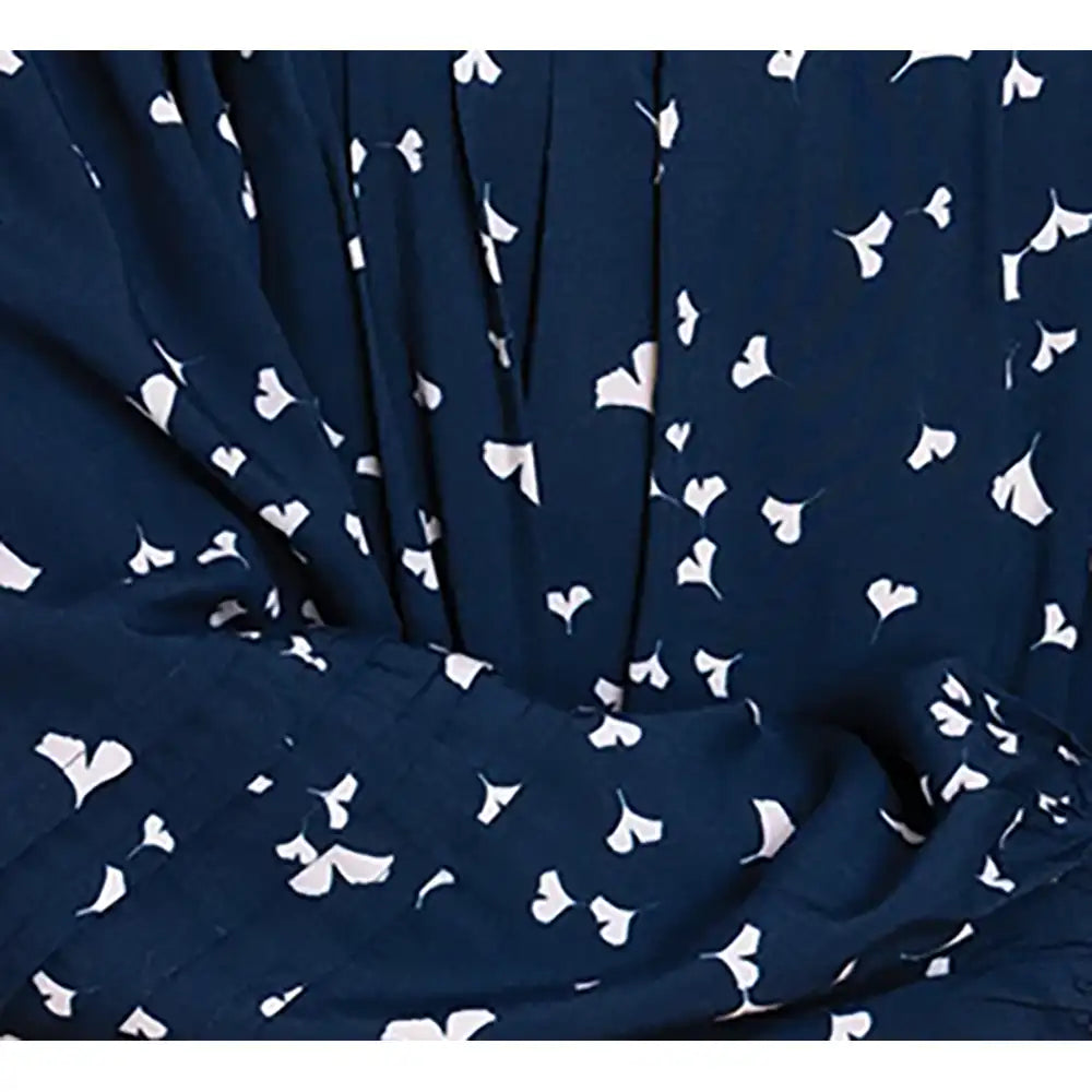 A close-up of a navy blue fabric with a white ginkgo leaf pattern, shown with soft folds and pleats.