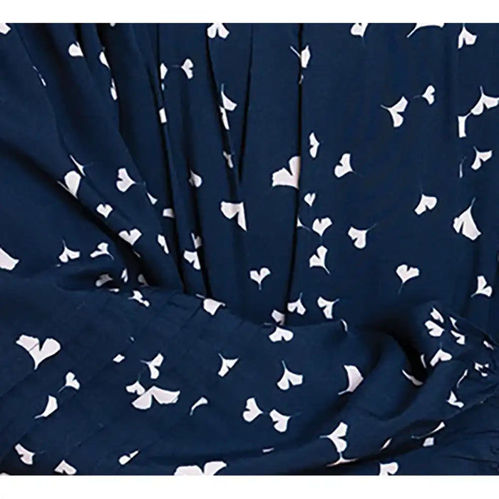 A close-up of a navy blue fabric with a white ginkgo leaf pattern, shown with soft folds and pleats.
