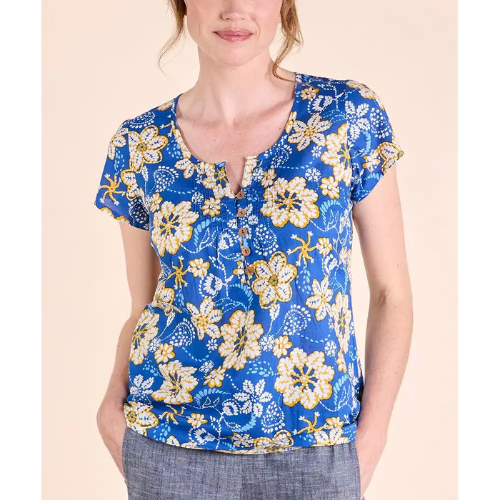 Bright blue top with short sleeves and round neckline. Neckline has a v notch in with and 5 brown buttons. White and yellow flowers printed on top. 