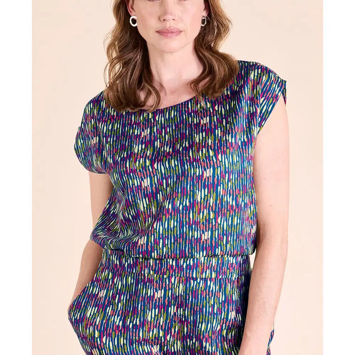 A woman wearing a colorful abstract-patterned short-sleeve top and matching bottoms against a plain beige background.