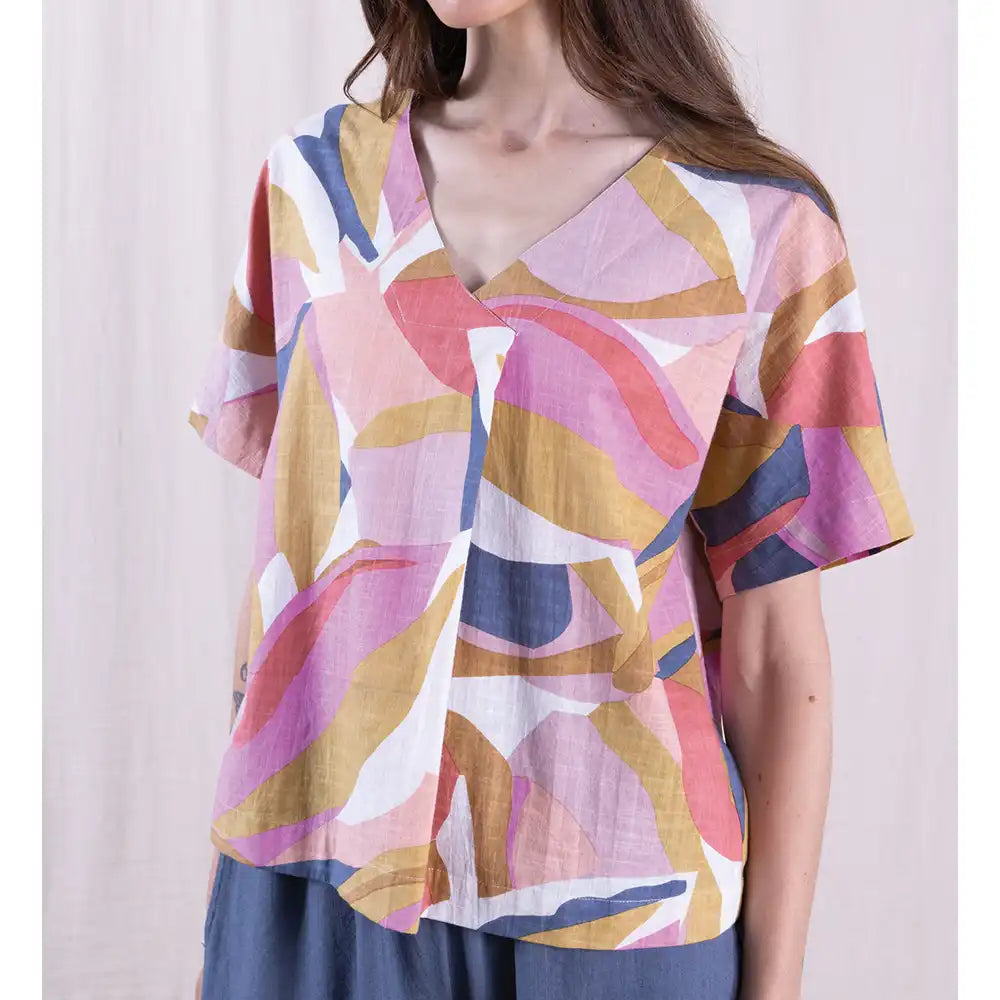 Woman wearing a colorful abstract patterned top against a plain background