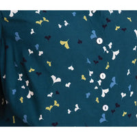 A close-up of a dark teal fabric with a repeating pattern of small ginkgo leaves in white, light blue, yellow, and dark navy, accented by two white buttons.
