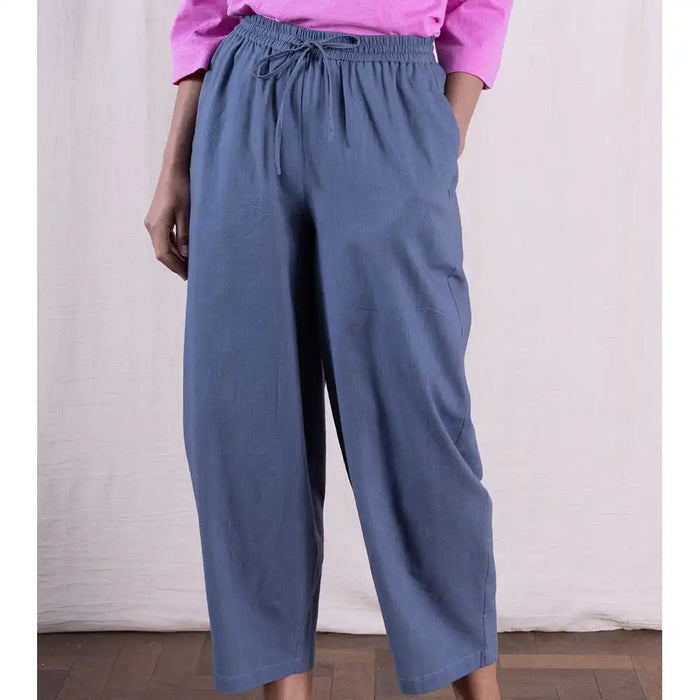 Person wearing blue wide-leg pants and a pink top against a neutral background