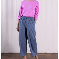 Person wearing a pink top and blue pants against a plain background