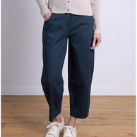 Person wearing navy wide-leg pants and white sneakers on a wooden floor.