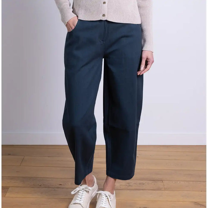 Person wearing navy wide-leg pants and white sneakers on a wooden floor.