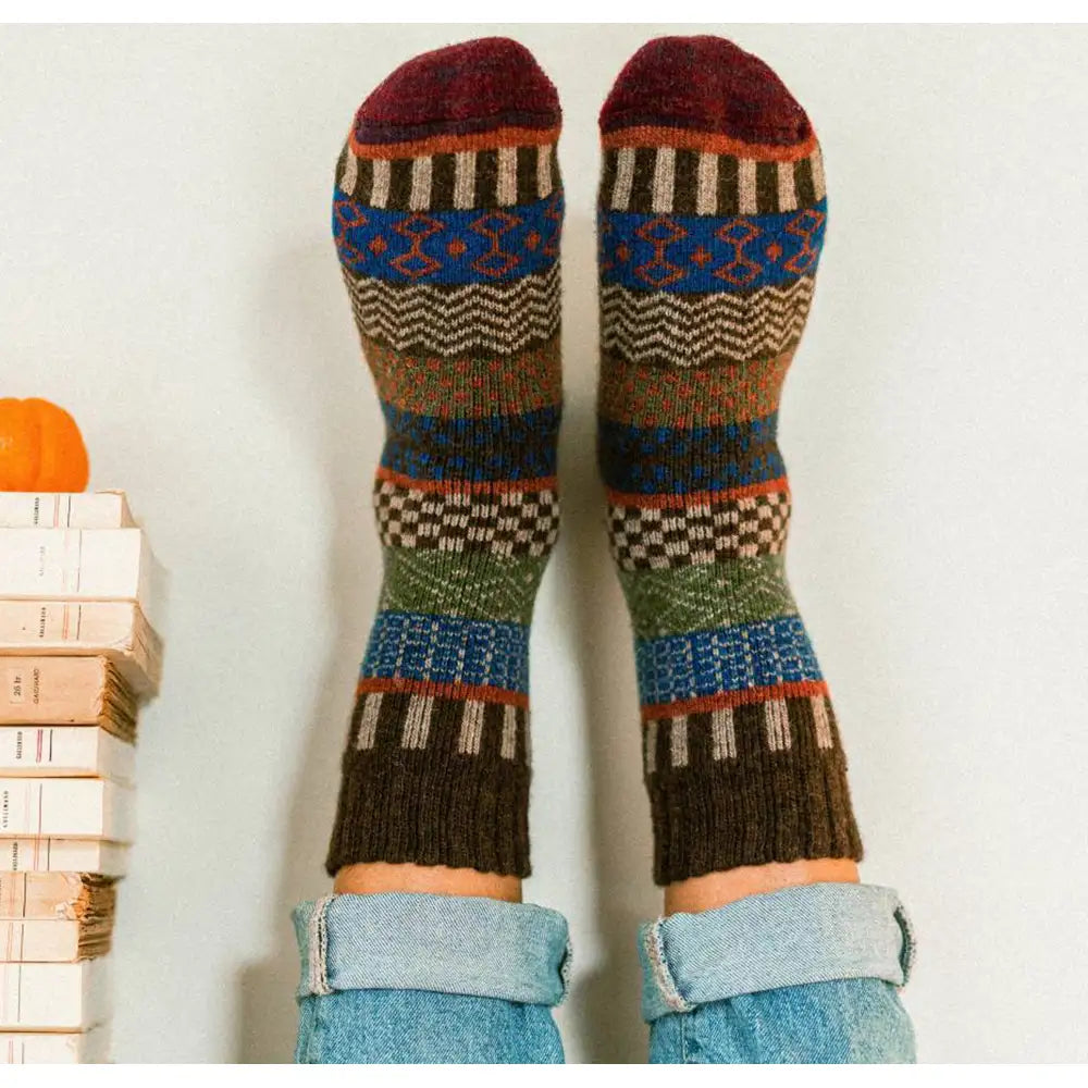 Colorful patterned socks worn with light blue jeans on a white background