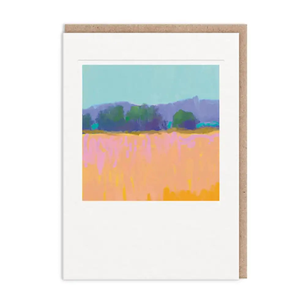 A white greeting card with a kraft brown envelope behind it, featuring a colorful abstract landscape painting of a field and trees.