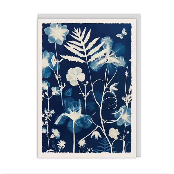 A botanical art print or card featuring white and light blue floral silhouettes on a dark navy blue background, shown against a clean white backdrop.