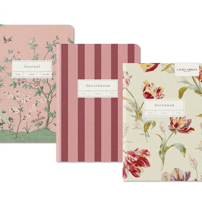 Three Laura Ashley stationery items arranged overlapping on a white background: a floral journal, a pink striped sketchbook, and a floral notebook.