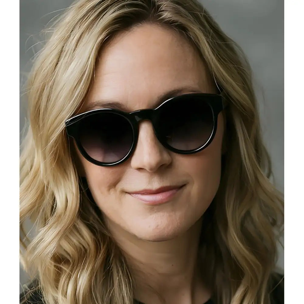 Woman wearing black sunglasses with a neutral background