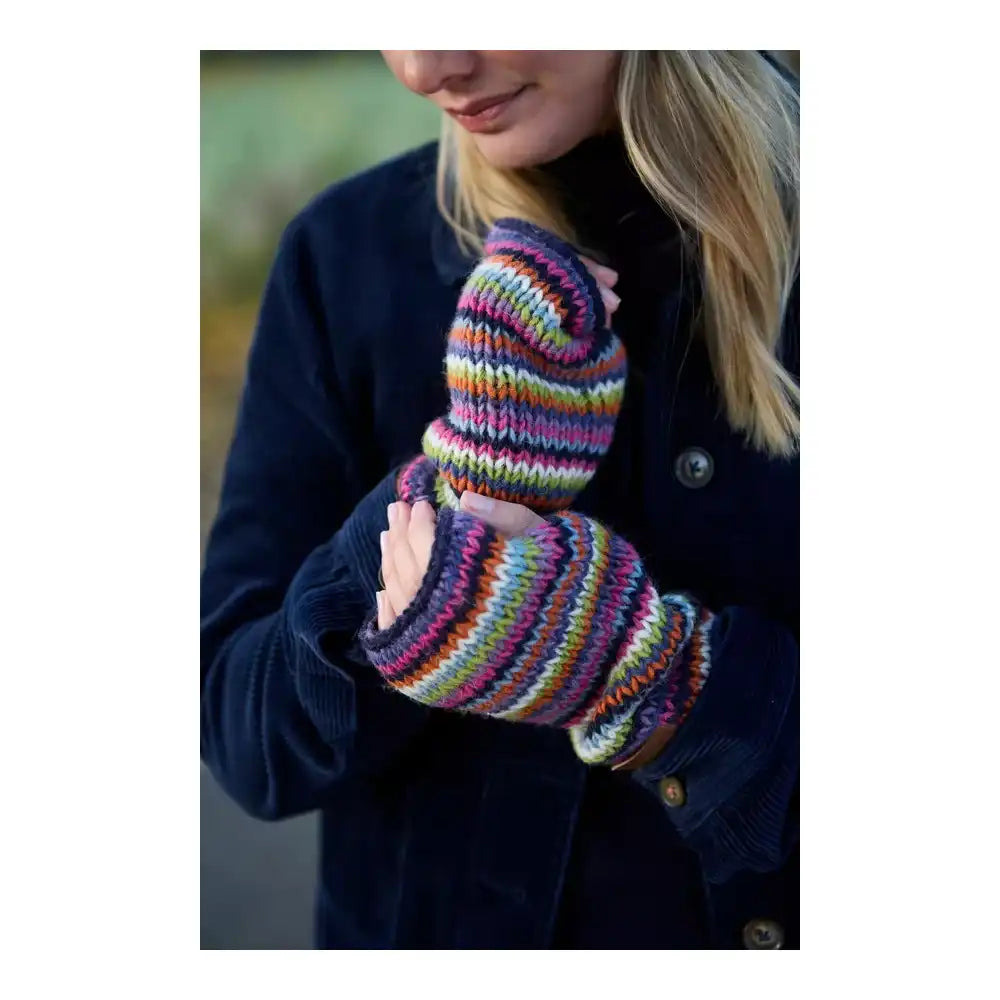 A close-up of a person wearing multicolored striped knit fingerless gloves over a dark navy coat, with the lower face and hair partially visible.