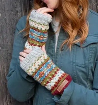 Person wearing colorful knitted fingerless gloves against a wooden background