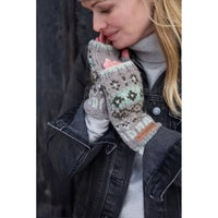 A woman wearing a pair of knit fingerless gloves with a grey base and green, brown, and white Fair Isle style patterns, paired with a grey turtleneck and a dark denim jacket.