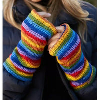 A person wearing a pair of long, rainbow-striped knit fingerless gloves or wrist warmers over a dark puffer jacket.