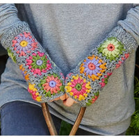 Colorful flower-patterned crocheted arm warmers worn by a person.