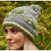 Woman wearing a gray knit hat with green floral patterns against a natural background