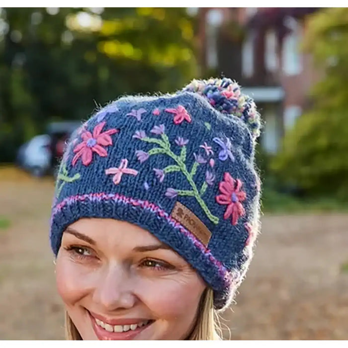 Woman wearing a blue knitted hat with floral patterns outdoors