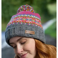 Person wearing a gray knit beanie with a colorful pom-pom and Pachamama label.