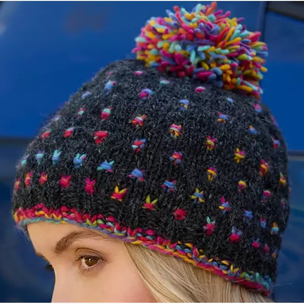 Knitted hat with colorful pom-pom on a blue background