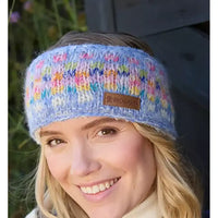Woman wearing a colorful knitted headband with a brand label, outdoors.