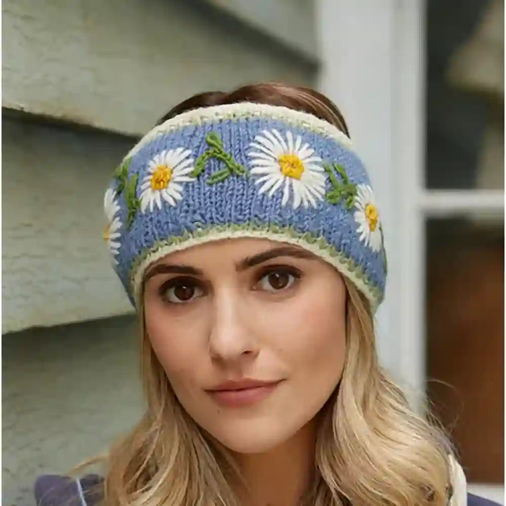 Pale blue wool head band with white daisies embroidered on it. Green leaves between white flowers and every flower has a yellow centre. White trim.