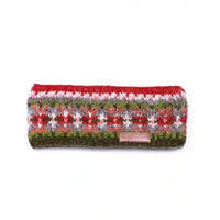 A knitted headband with a multicolor Fair Isle pattern featuring red, green, white, and gray, with a small pink brand tag at the front.