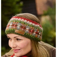 A woman wearing a knitted headband with a multicolor pattern of red, green, white, and orange, featuring a small brown leather patch on the front.