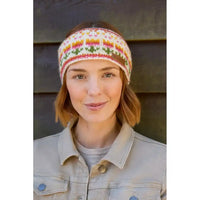 A woman wearing a knitted headband with a colorful floral pattern, paired with a light beige denim jacket, set against a dark wooden background.